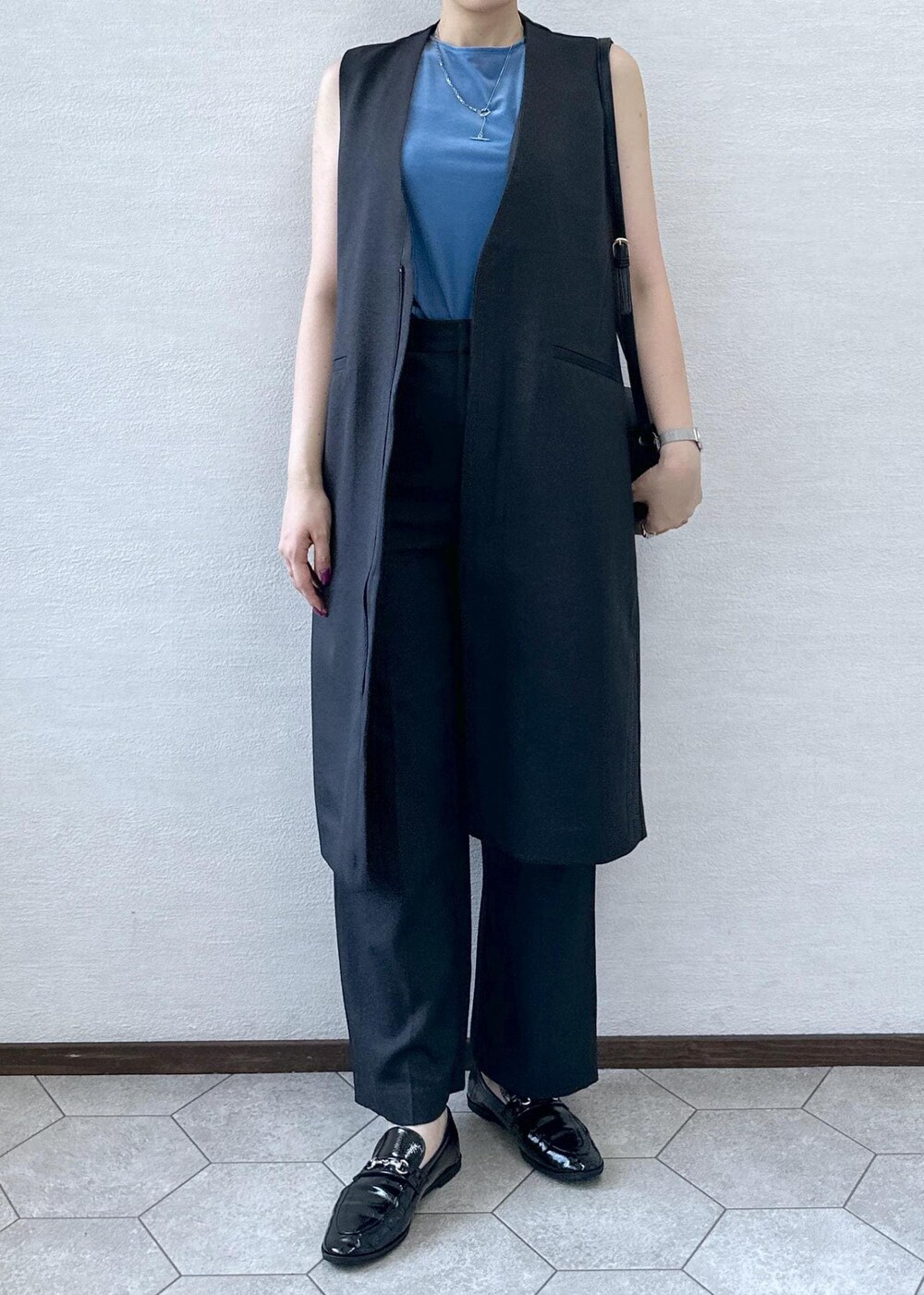 ブラック系のショルダーバッグ、ブルー系のTシャツ/カットソー、グレー系のベストを着用したレディースの秋コーディネートの4枚目の写真