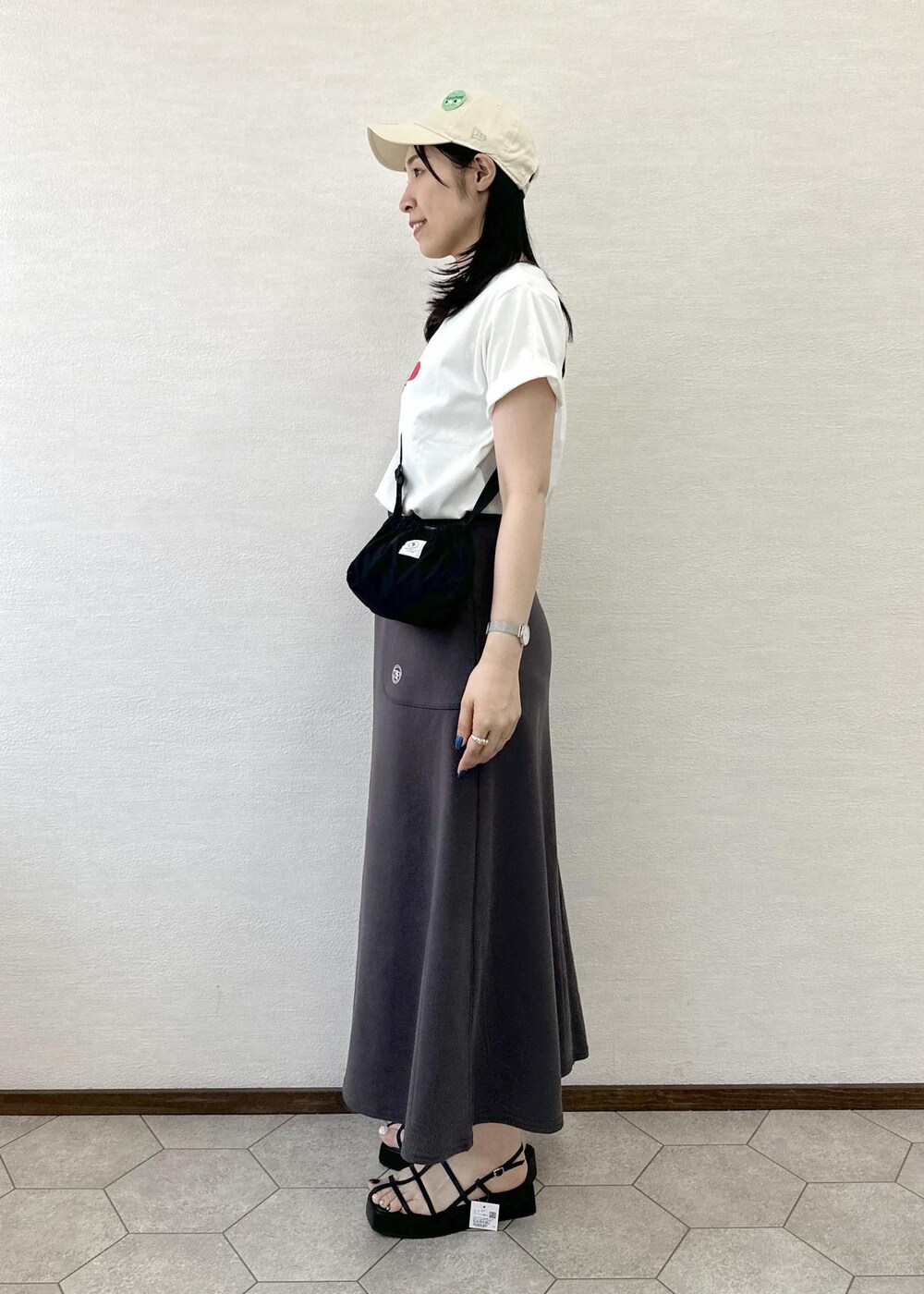 ブラック系のショルダーバッグ、グレー系のスカート、ブラック系のサンダルを着用したレディースの春コーディネートの3枚目の写真