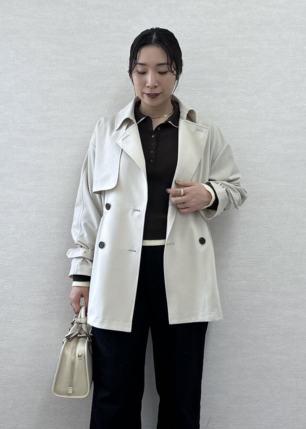 ホワイト系のボストンバッグ、ブルー系のチノパンツ、ベージュ系のトレンチコートを着用したレディースの春コーディネートの6枚目の写真