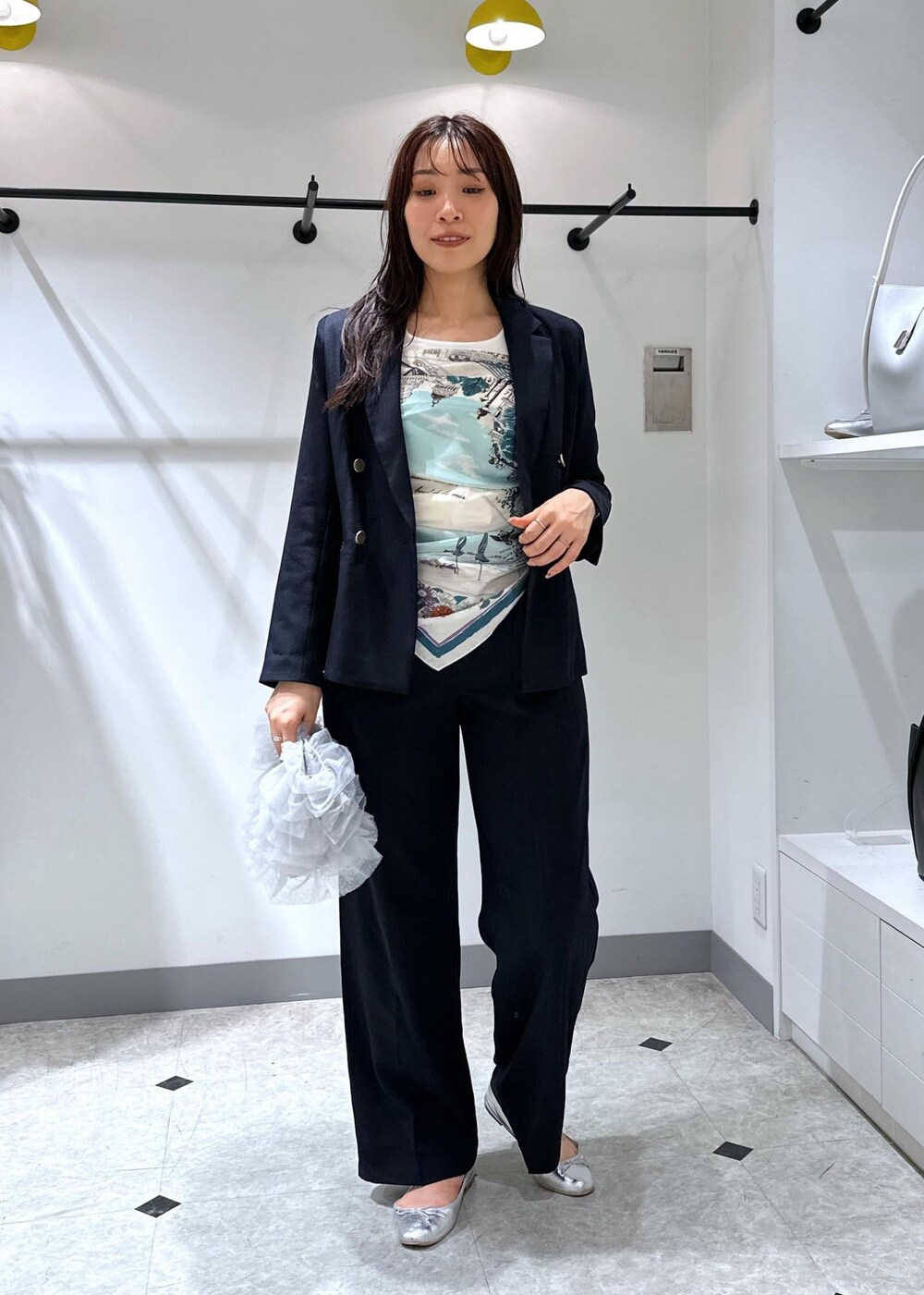 シルバー系のバレエシューズ、グレー系のショルダーバッグ、ブルー系のスラックスを着用したレディースの夏コーディネートの2枚目の写真