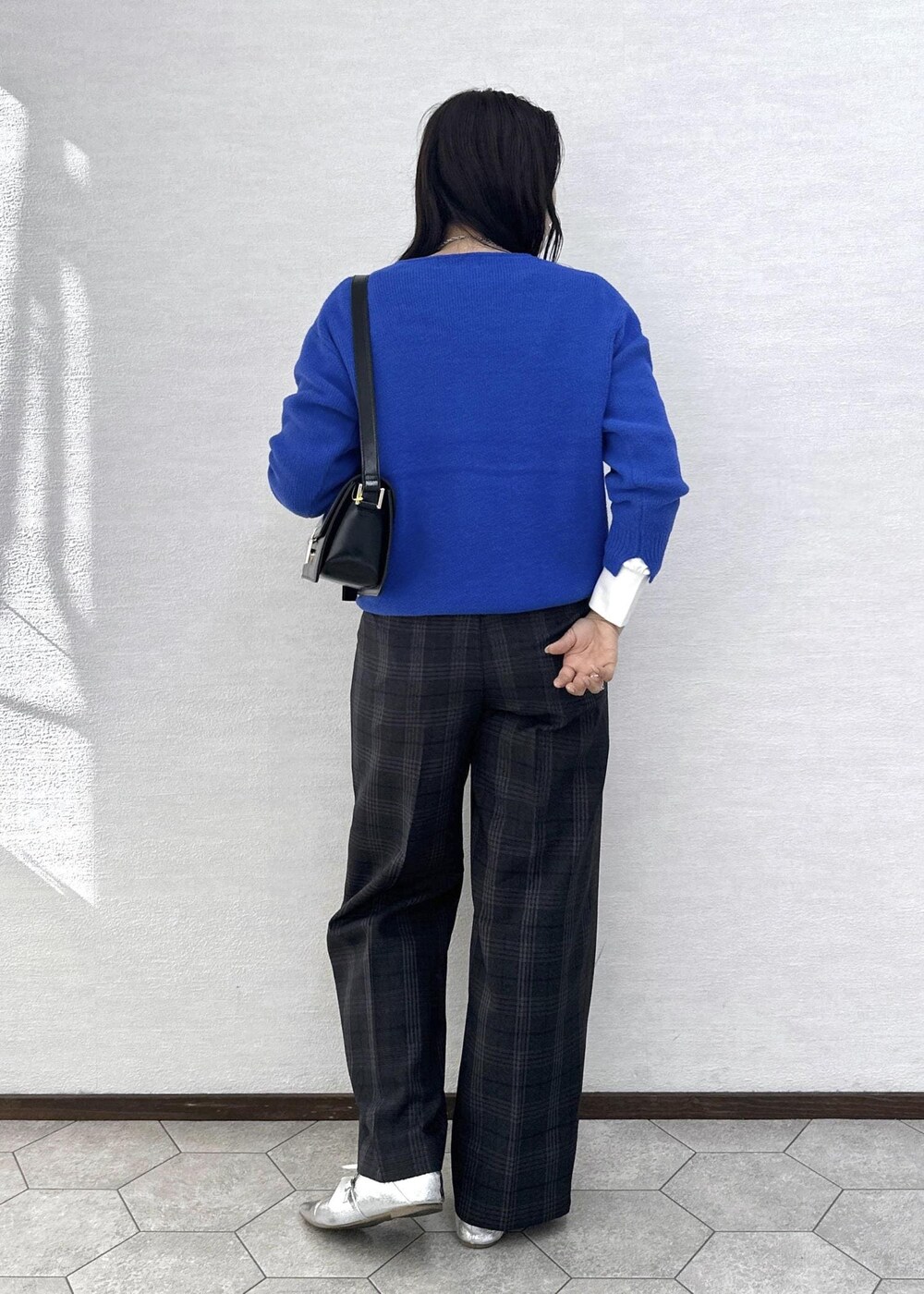 ブラック系のショルダーバッグ、ブルー系のニット/セーター、ホワイト系のTシャツ/カットソーを着用したレディースの秋コーディネートの6枚目の写真