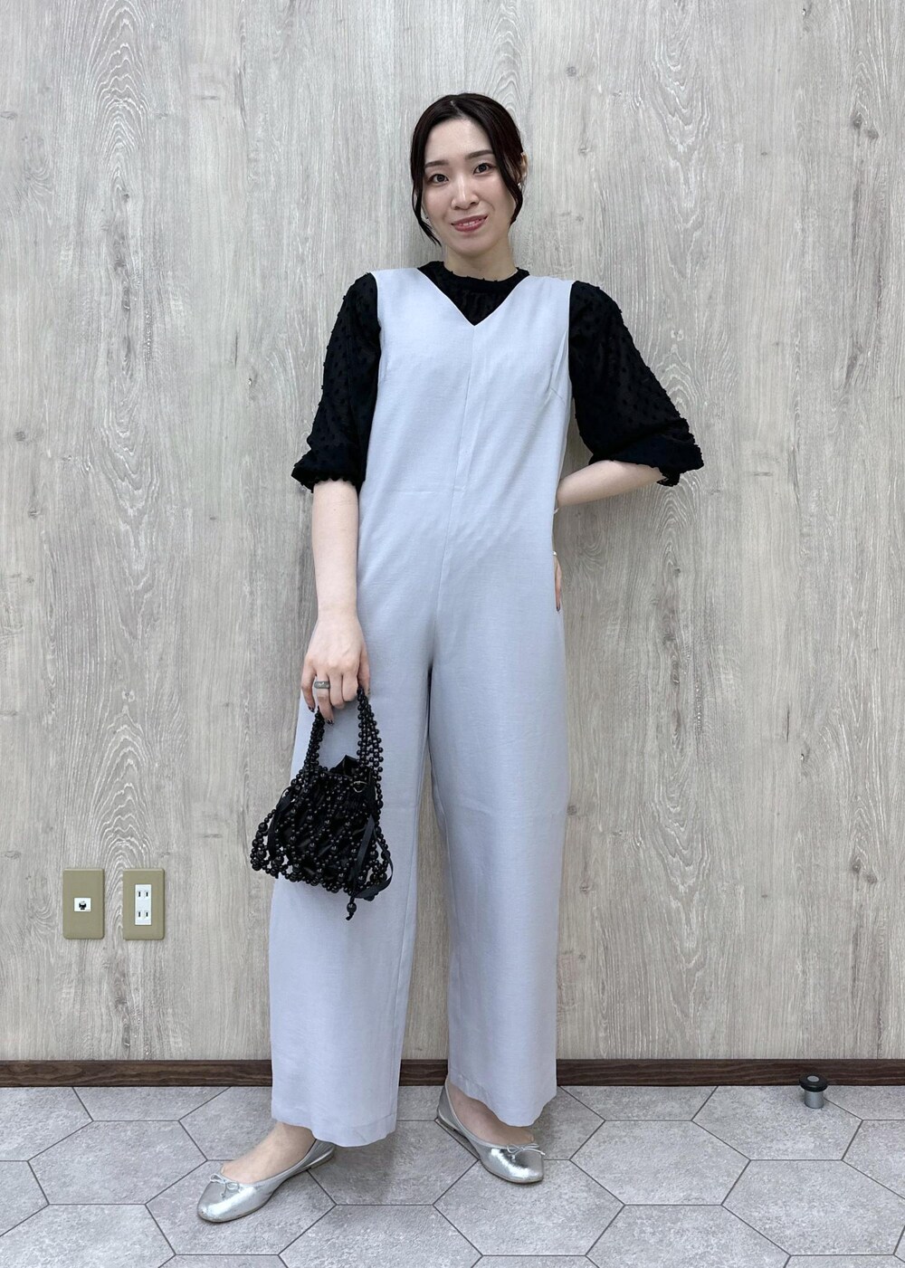シルバー系のバレエシューズ、ブラック系のハンドバッグ、グレー系のつなぎ/オールインワンを着用したレディースの春コーディネートの2枚目の写真