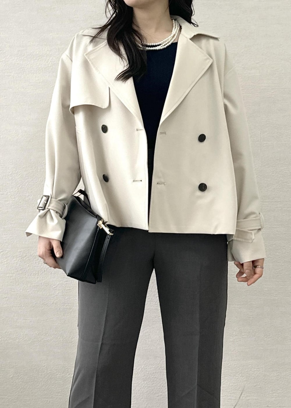 ブラック系のショルダーバッグ、ブルー系のニット/セーター、ベージュ系のトレンチコートを着用したレディースの春コーディネートの6枚目の写真