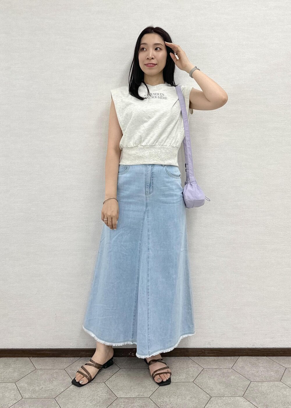 パープル系のショルダーバッグ、ホワイト系のスウェット、ブルー系のデニムスカートを着用したレディースの夏コーディネートの2枚目の写真