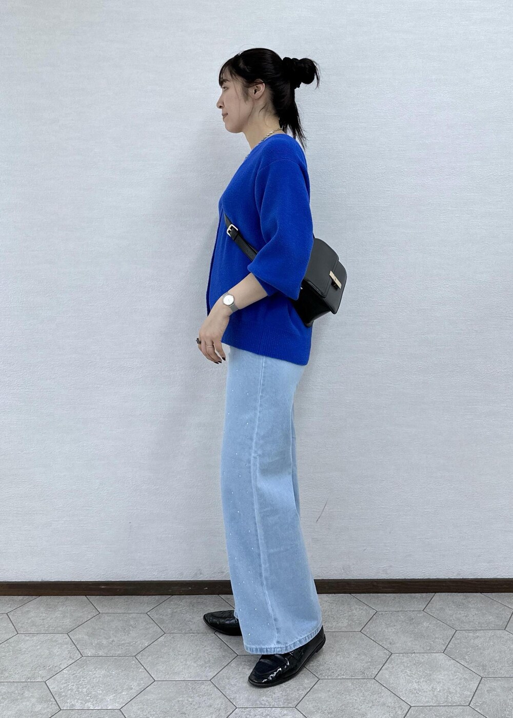 ブルー系のカーディガン/ボレロ、ブラック系のショルダーバッグ、ブルー系のデニムパンツを着用したレディースの秋コーディネートの5枚目の写真