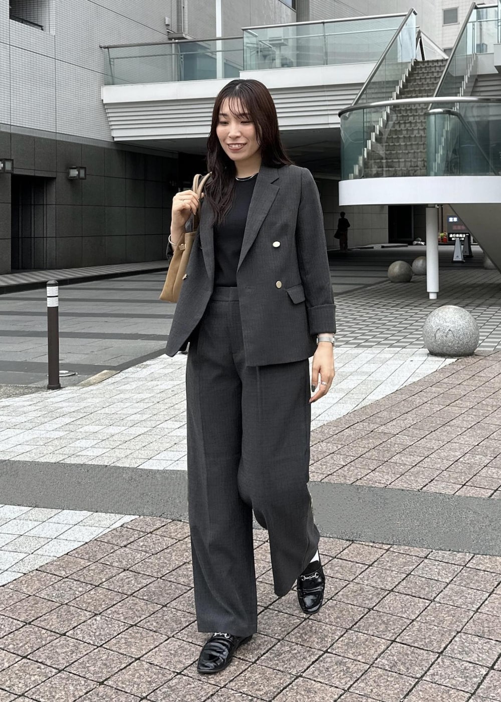 ブラック系のタンクトップ、イエロー系のトートバッグ、ブラック系のテーラードジャケットを着用したレディースの秋コーディネートの2枚目の写真