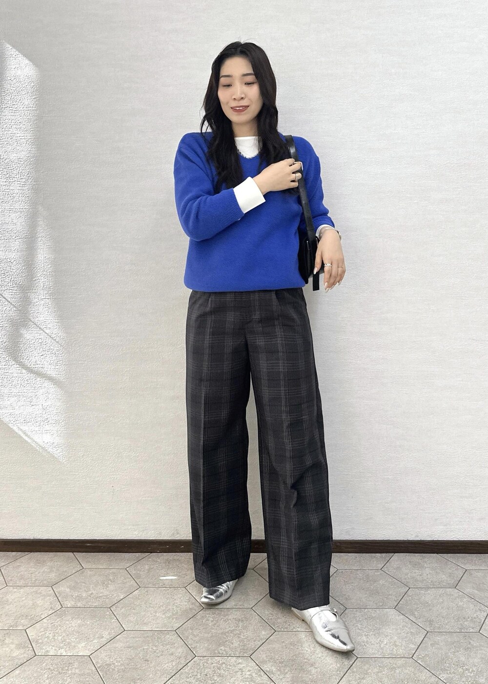 ブラック系のショルダーバッグ、ブルー系のニット/セーター、ホワイト系のTシャツ/カットソーを着用したレディースの秋コーディネートの3枚目の写真