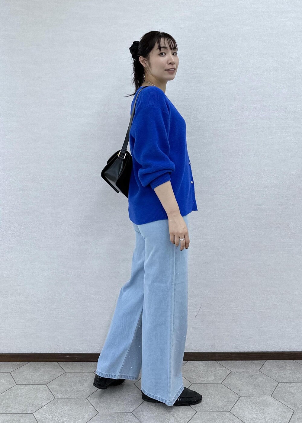 ブルー系のカーディガン/ボレロ、ブラック系のショルダーバッグ、ブルー系のデニムパンツを着用したレディースの秋コーディネートの4枚目の写真