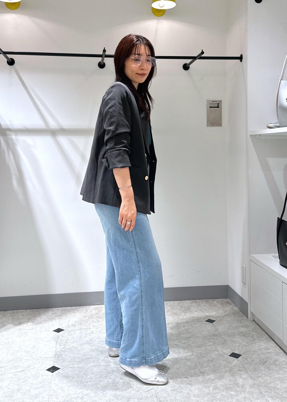 シルバー系のバレエシューズ、ブラック系のトートバッグ、ブルー系のデニムパンツを着用したレディースの夏コーディネートの4枚目の写真