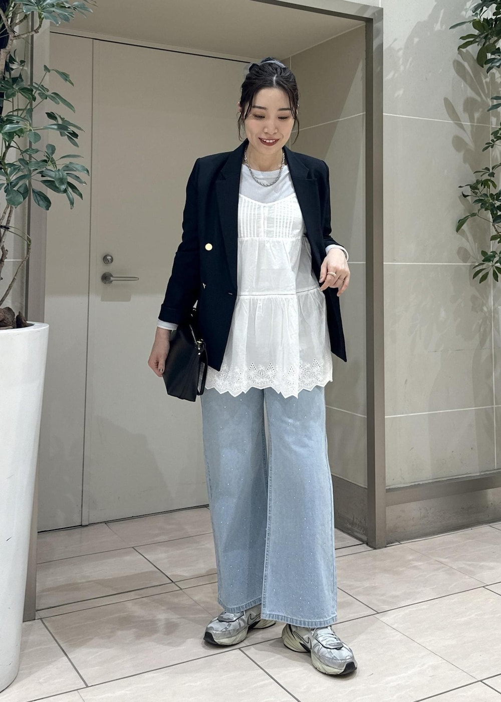 ブルー系のデニムパンツ、ブラック系のショルダーバッグ、ブルー系のテーラードジャケットを着用したレディースの冬コーディネートの2枚目の写真