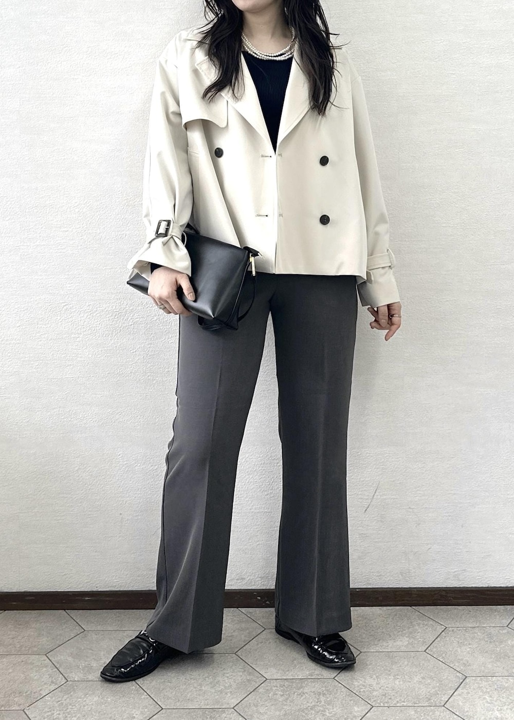 ブラック系のショルダーバッグ、ブルー系のニット/セーター、ベージュ系のトレンチコートを着用したレディースの春コーディネートの5枚目の写真