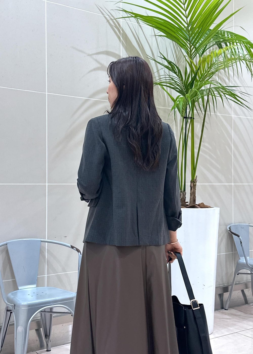 ブラック系のショルダーバッグ、ブラック系のテーラードジャケット、ブラウン系のスカートを着用したレディースの秋コーディネートの9枚目の写真