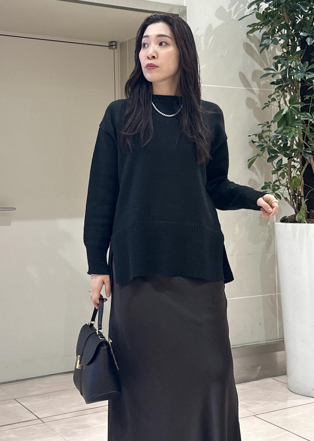 ブラック系のニット/セーター、ブラック系のショルダーバッグ、ブラウン系のスカートを着用したレディースの冬コーディネートの7枚目の写真