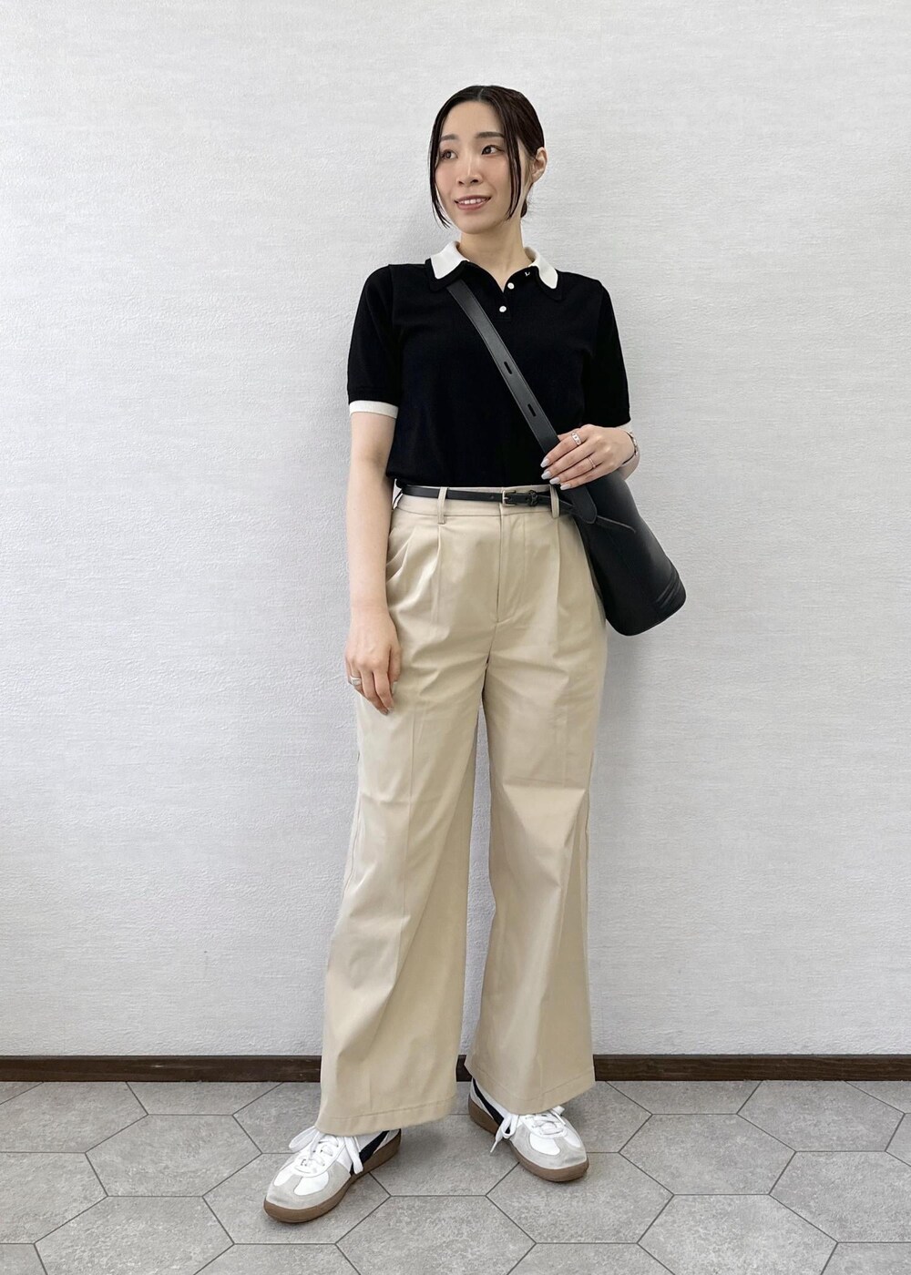 ベージュ系のチノパンツ、ブラック系のトートバッグ、ブラック系のポロシャツを着用したレディースの春コーディネートの2枚目の写真