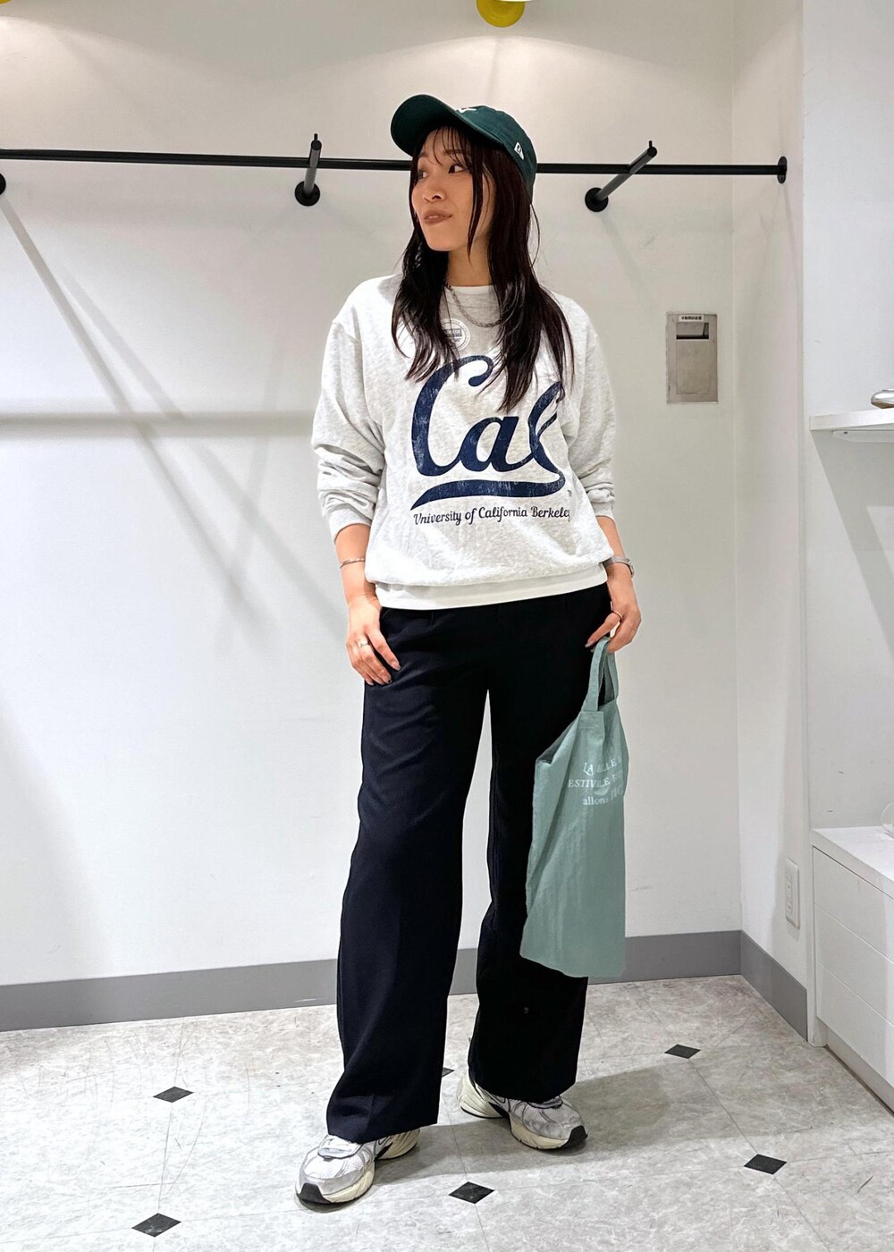 グレー系のスウェット、ブルー系のトートバッグ、ブルー系のスラックスを着用したレディースの夏コーディネートの2枚目の写真