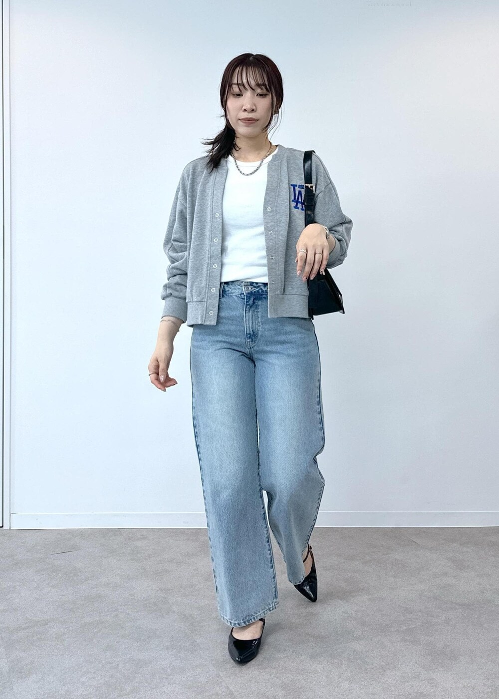 グレー系のデニムパンツ、ホワイト系のタンクトップ、ブラック系のショルダーバッグを着用したレディースの夏コーディネートの4枚目の写真