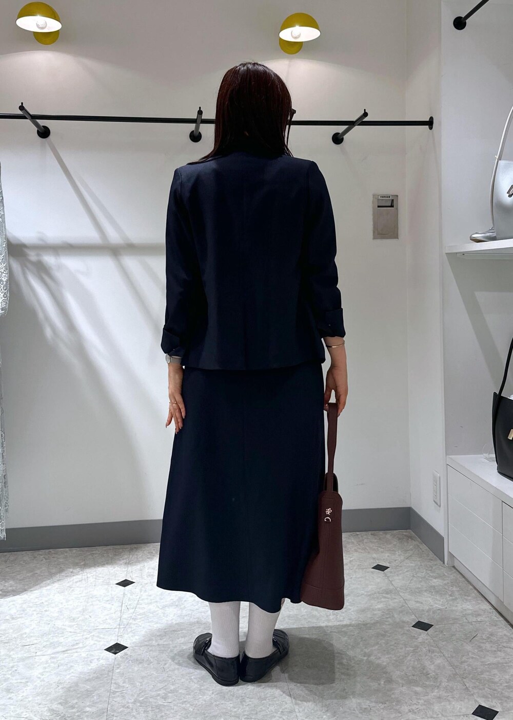 ブルー系のベスト、レッド系のショルダーバッグ、ホワイト系のタンクトップを着用したレディースの夏コーディネートの6枚目の写真