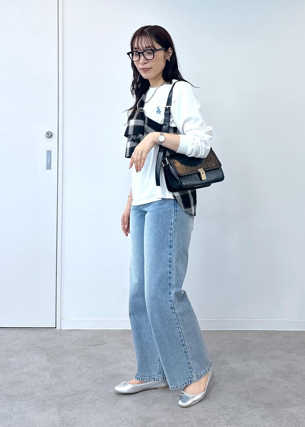 ブルー系のデニムパンツ、シルバー系のバレエシューズ、ブラック系のショルダーバッグを着用したレディースの夏コーディネートの4枚目の写真