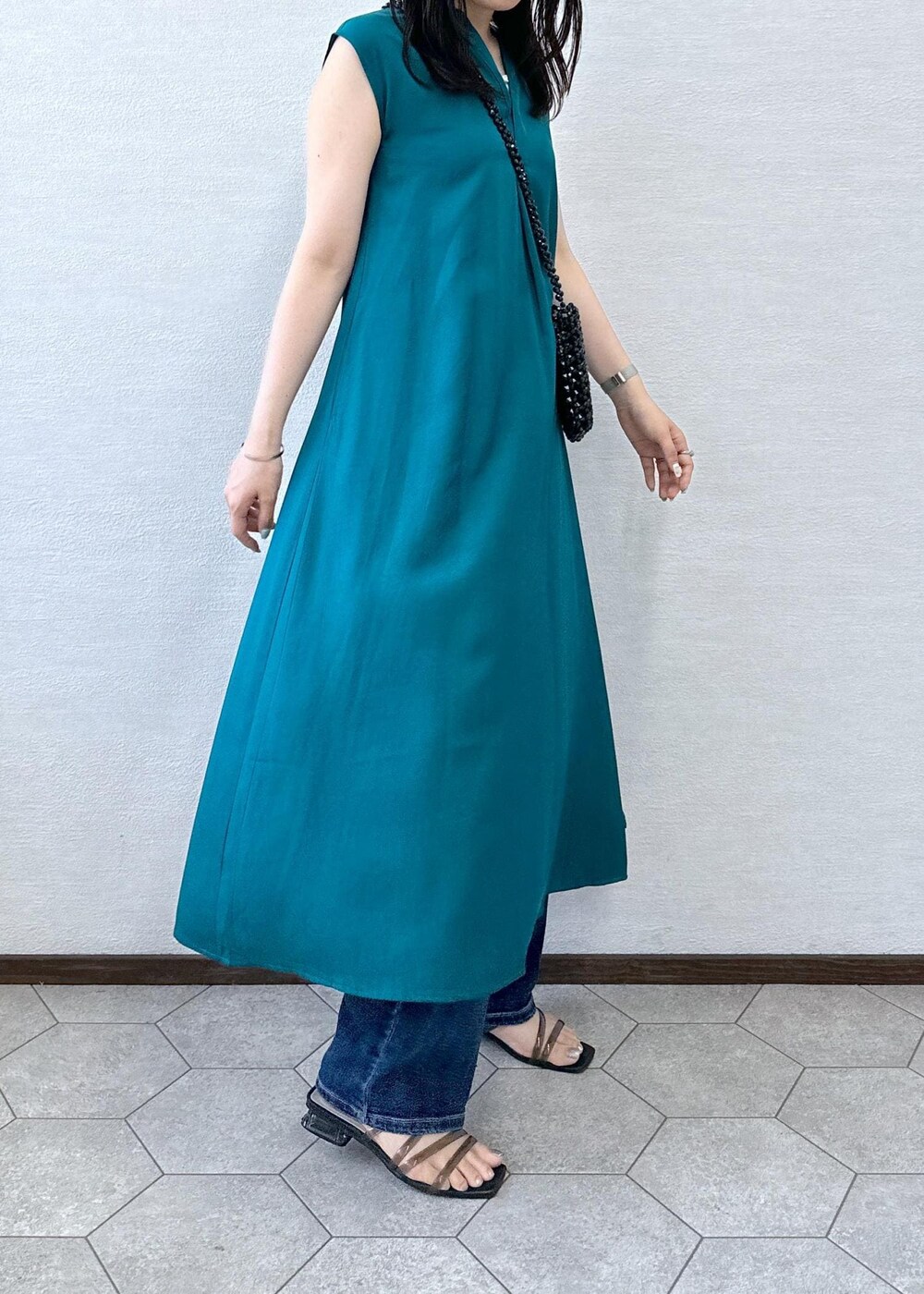 ブラック系のショルダーバッグ、ブルー系のデニムパンツ、グリーン系のワンピースを着用したレディースの夏コーディネートの6枚目の写真