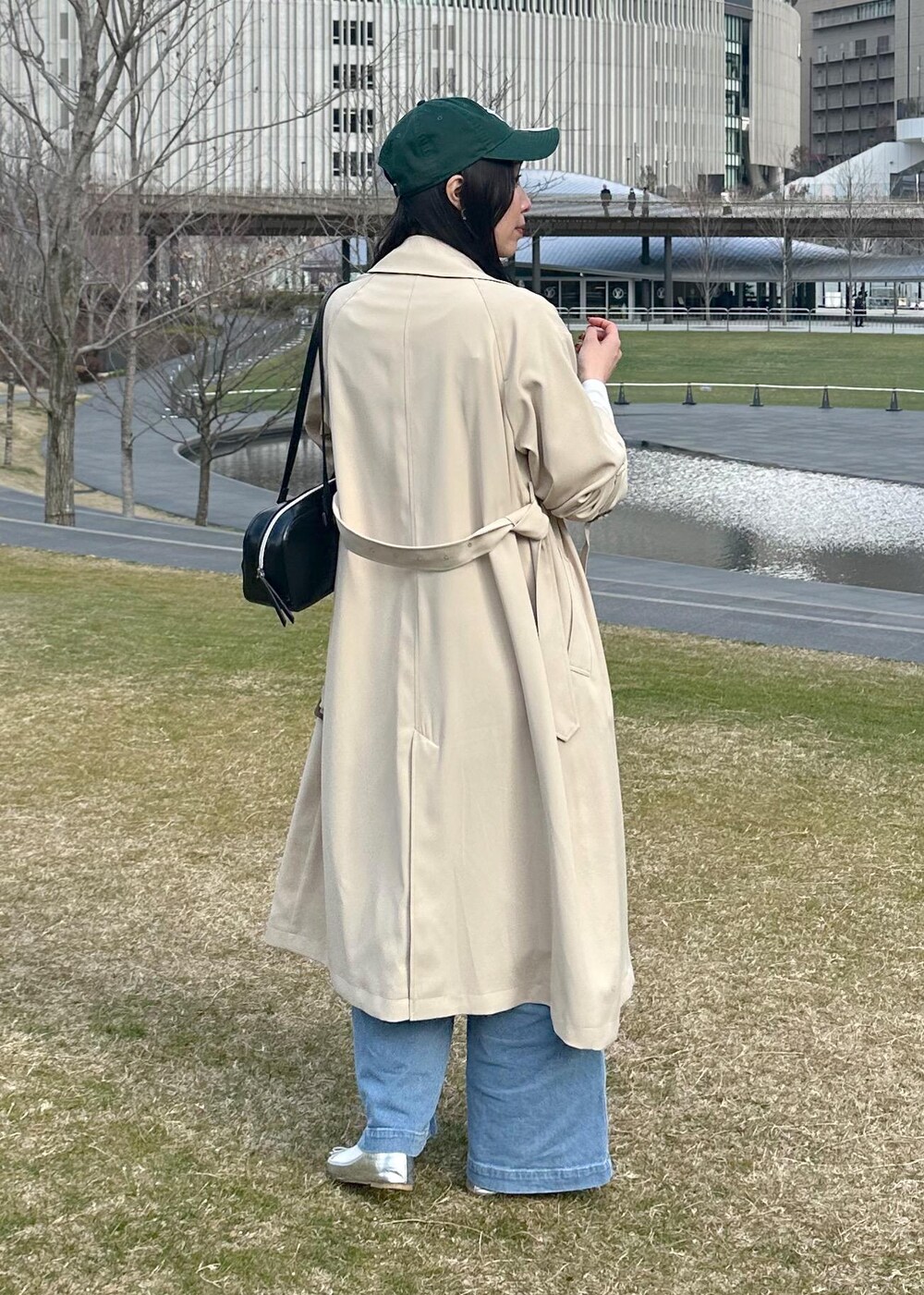 ブラック系のボストンバッグ、ブルー系のベスト、ベージュ系のトレンチコートを着用したレディースの冬コーディネートの3枚目の写真