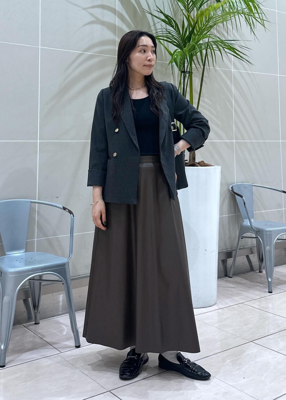 ブラック系のショルダーバッグ、ブラック系のテーラードジャケット、ブラウン系のスカートを着用したレディースの秋コーディネートの2枚目の写真