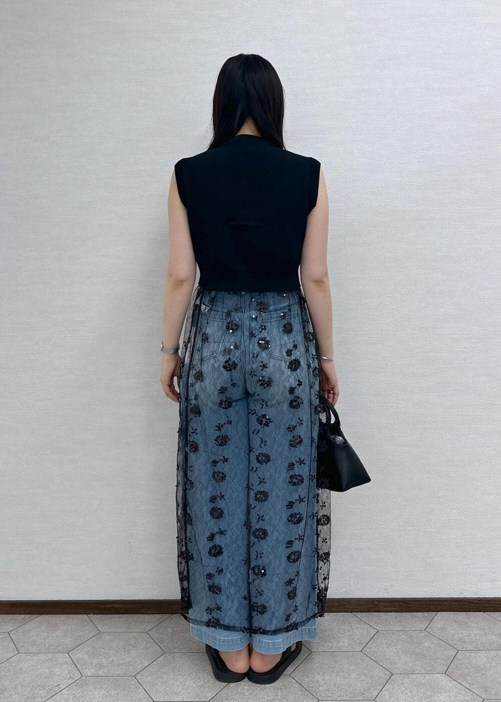 ブルー系のデニムパンツ、ブラック系のベスト、ブラック系のショルダーバッグを着用したレディースの夏コーディネートの7枚目の写真