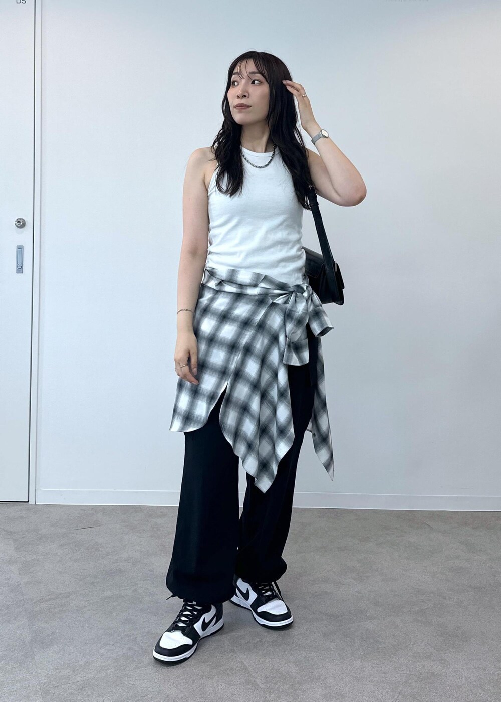 ブラック系のカーゴパンツ、ホワイト系のタンクトップ、ブラック系のショルダーバッグを着用したレディースの夏コーディネートの2枚目の写真