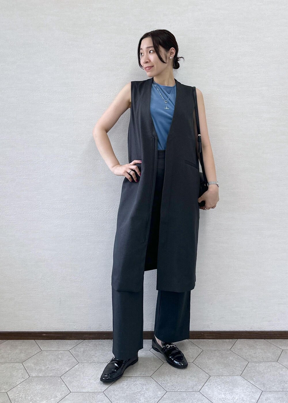 ブラック系のショルダーバッグ、ブルー系のTシャツ/カットソー、グレー系のベストを着用したレディースの秋コーディネートの2枚目の写真