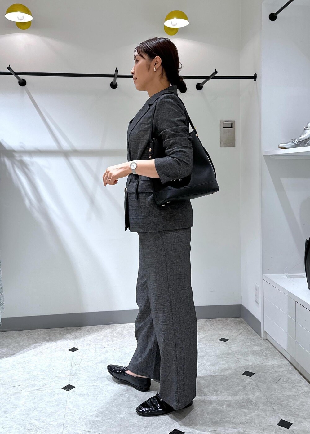 ブラック系のタンクトップ、グレー系のテーラードジャケット、グレー系のスラックスを着用したレディースの夏コーディネートの4枚目の写真