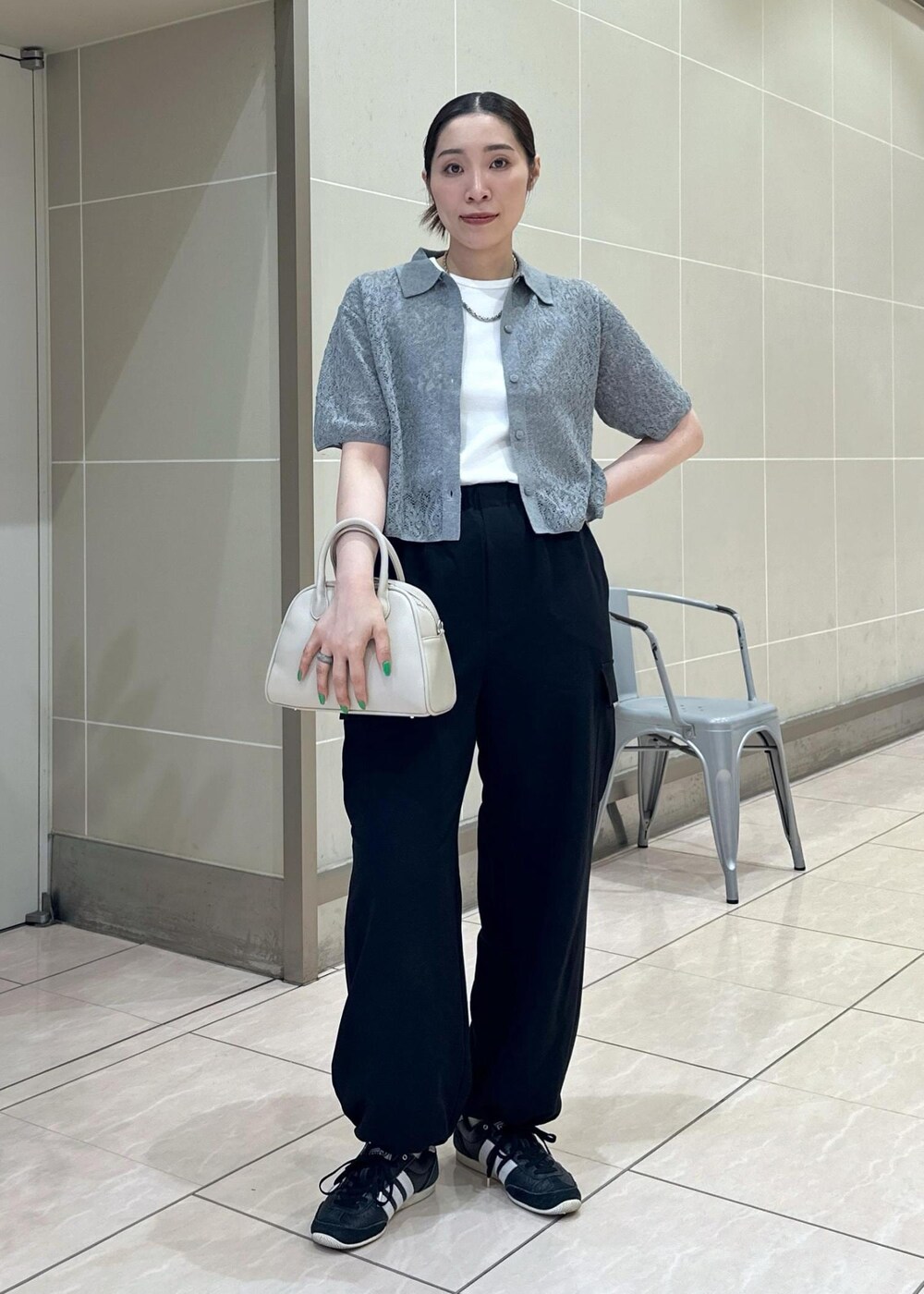 ベージュ系のボストンバッグ、ブラック系のカーゴパンツ、ホワイト系のタンクトップを着用したレディースの夏コーディネートの3枚目の写真