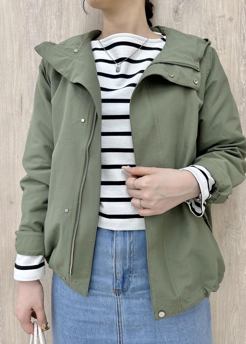 グリーン系のマウンテンパーカー、ホワイト系のTシャツ/カットソー、ブルー系のデニムスカートを着用したレディースの春コーディネートの3枚目の写真