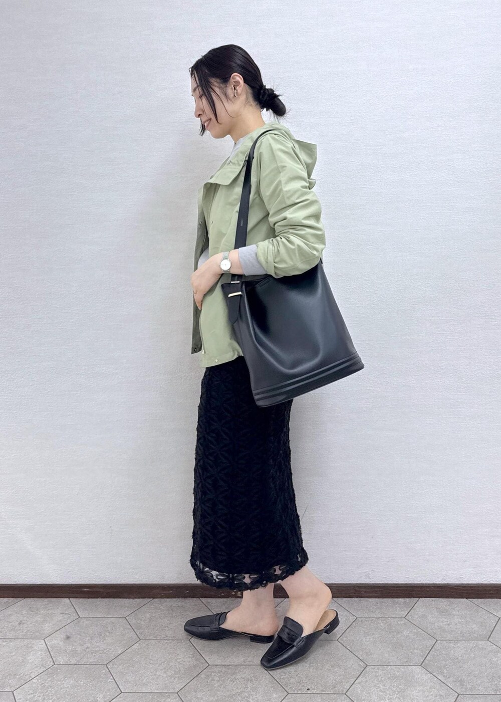 ブラック系のスカート、グレー系のニット/セーター、グリーン系のマウンテンパーカーを着用したレディースの春コーディネートの6枚目の写真