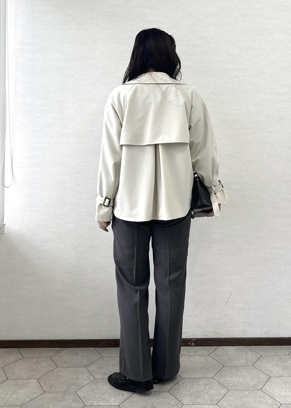 ブラック系のショルダーバッグ、ブルー系のニット/セーター、ベージュ系のトレンチコートを着用したレディースの春コーディネートの4枚目の写真