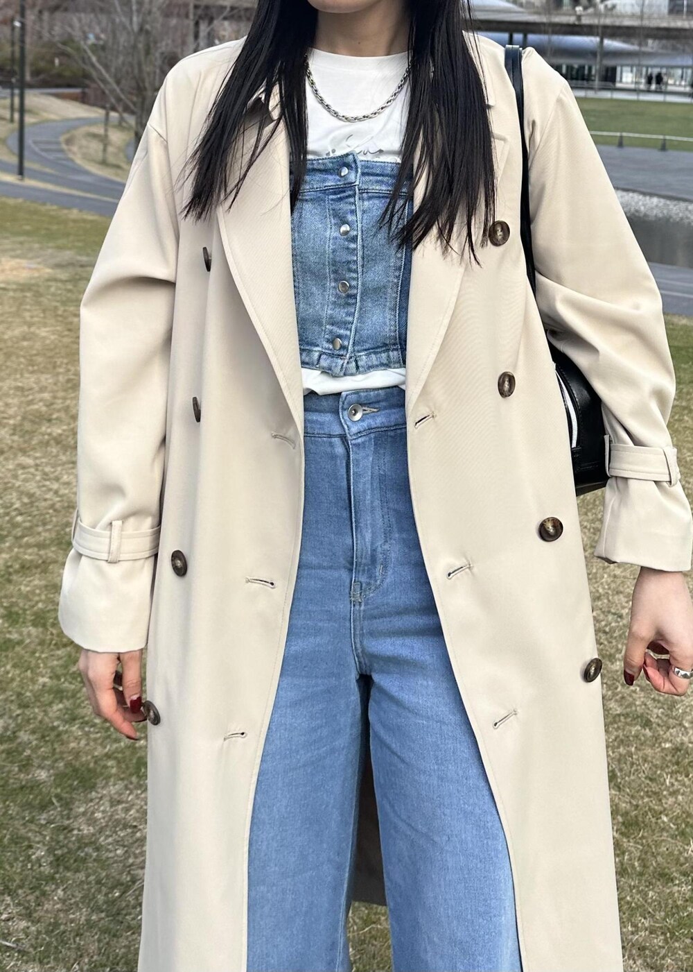 ブラック系のボストンバッグ、ブルー系のベスト、ベージュ系のトレンチコートを着用したレディースの冬コーディネートの5枚目の写真