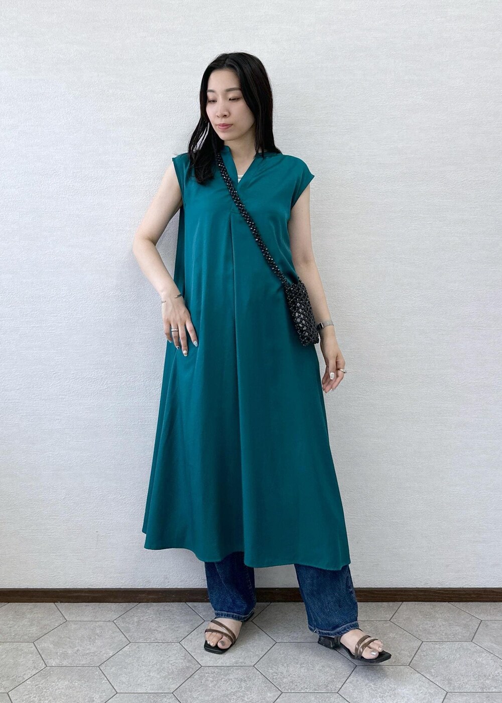 ブラック系のショルダーバッグ、ブルー系のデニムパンツ、グリーン系のワンピースを着用したレディースの夏コーディネートの2枚目の写真