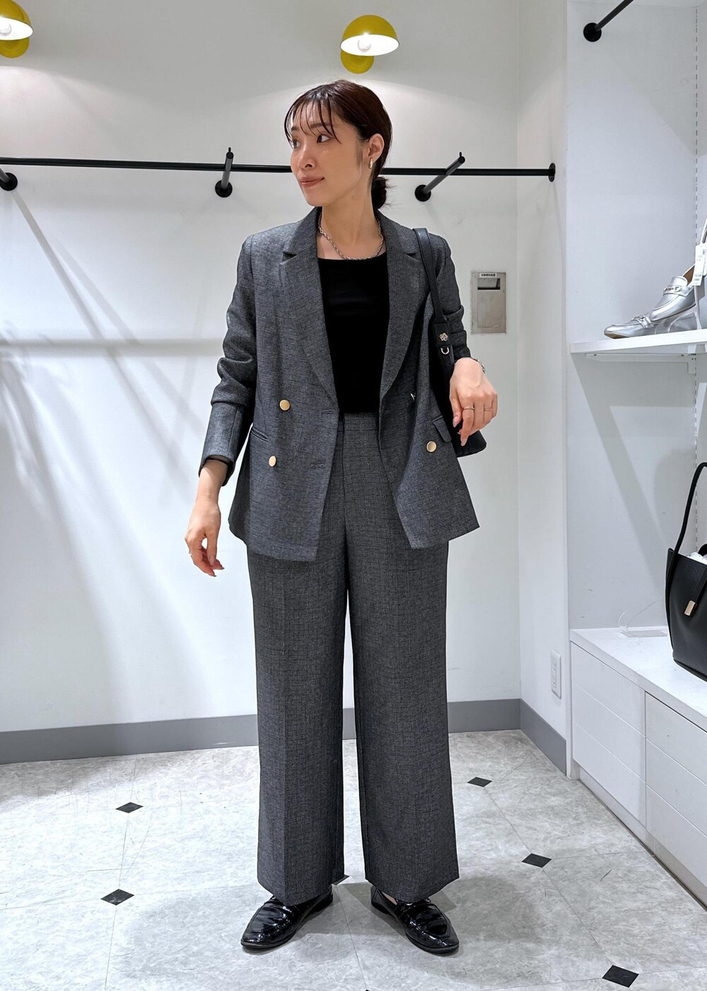 ブラック系のタンクトップ、グレー系のテーラードジャケット、グレー系のスラックスを着用したレディースの夏コーディネートの7枚目の写真