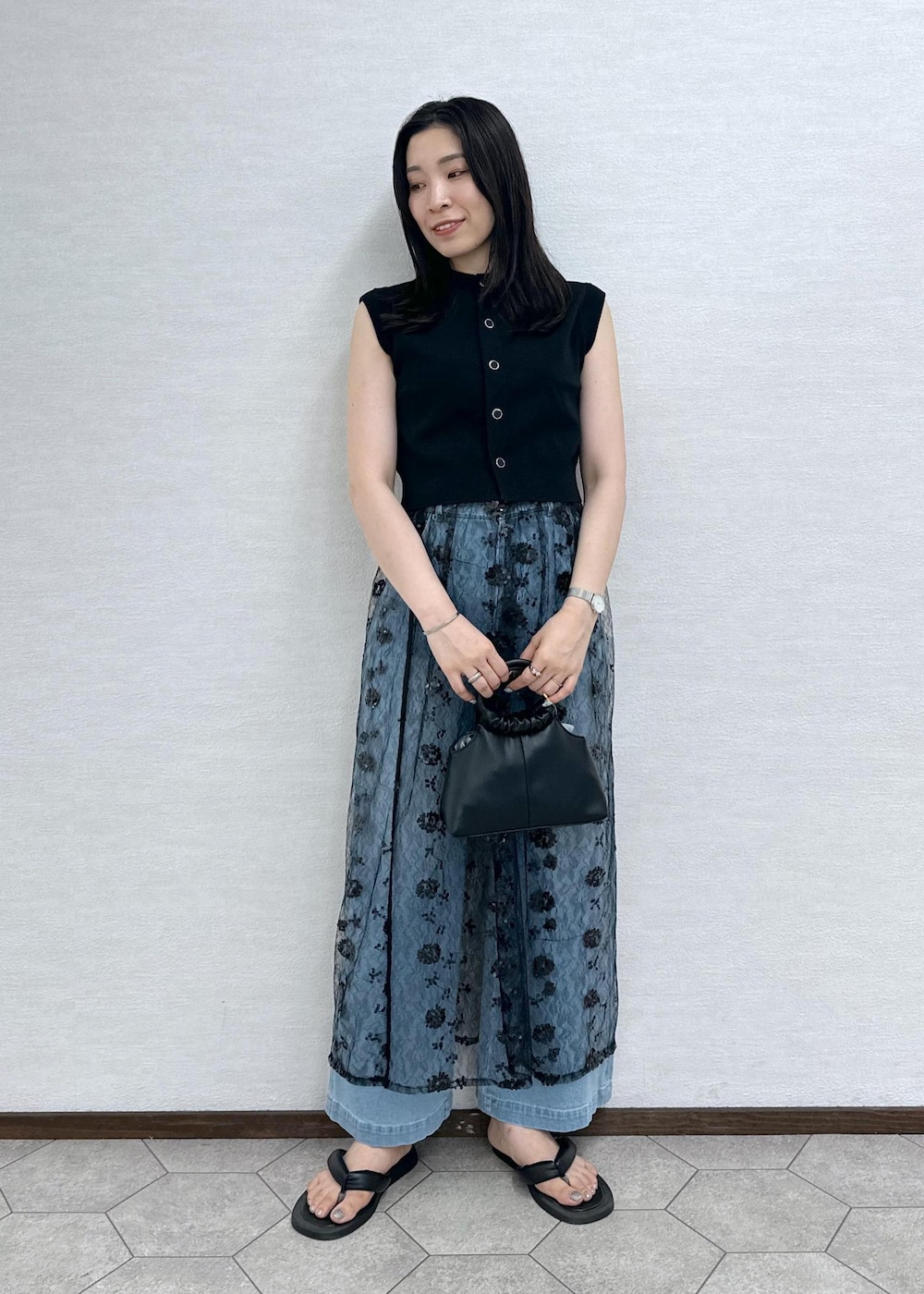 ブルー系のデニムパンツ、ブラック系のベスト、ブラック系のショルダーバッグを着用したレディースの夏コーディネートの5枚目の写真