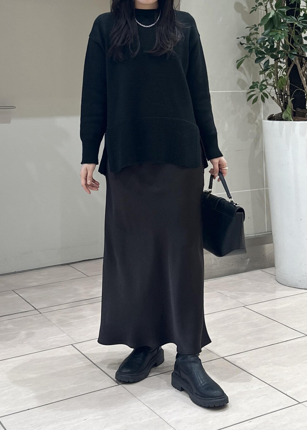 ブラック系のニット/セーター、ブラック系のショルダーバッグ、ブラウン系のスカートを着用したレディースの冬コーディネートの6枚目の写真