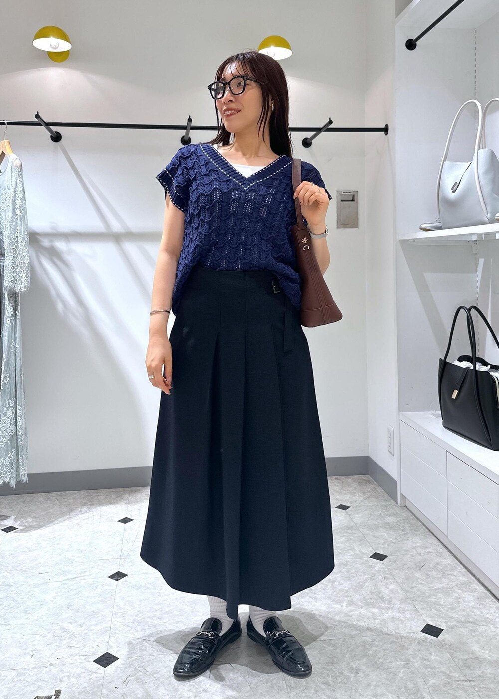 ブルー系のベスト、レッド系のショルダーバッグ、ホワイト系のタンクトップを着用したレディースの夏コーディネートの9枚目の写真