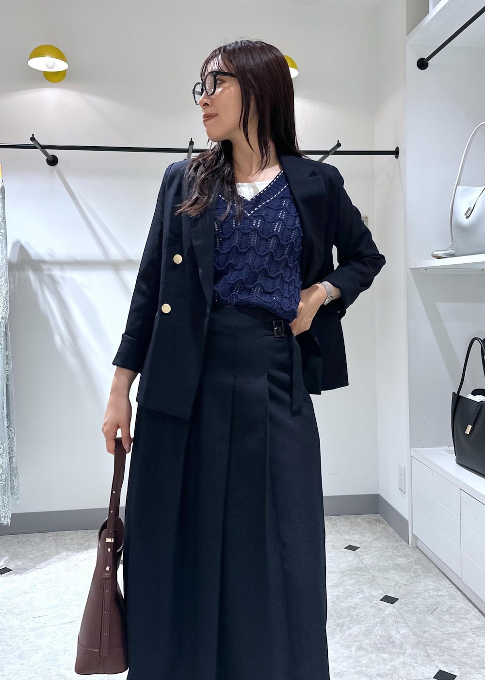 ブルー系のベスト、レッド系のショルダーバッグ、ホワイト系のタンクトップを着用したレディースの夏コーディネートの8枚目の写真