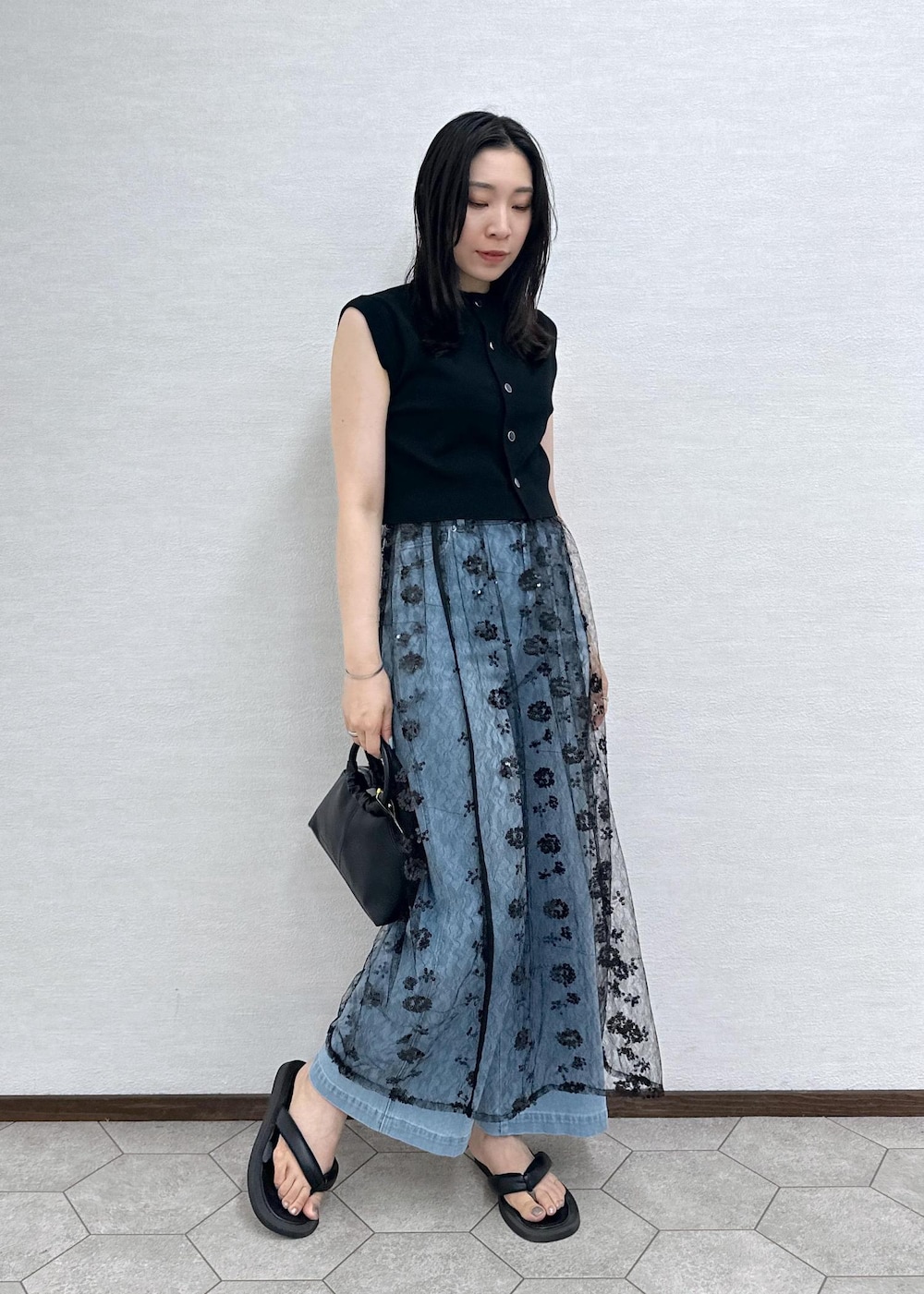 ブルー系のデニムパンツ、ブラック系のベスト、ブラック系のショルダーバッグを着用したレディースの夏コーディネートの2枚目の写真