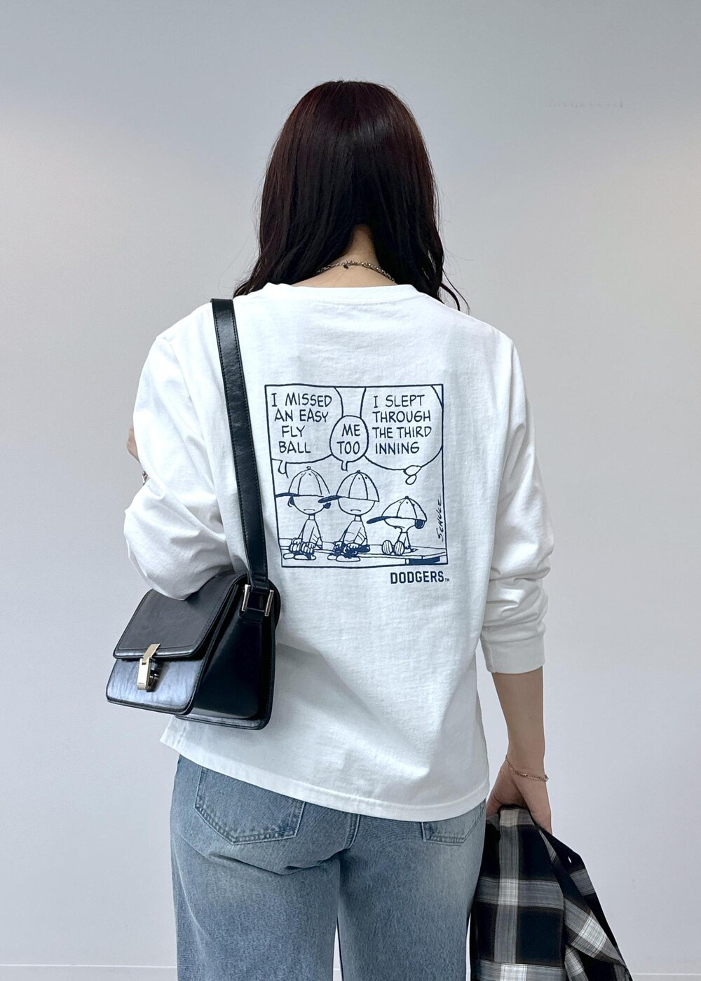 ブルー系のデニムパンツ、シルバー系のバレエシューズ、ブラック系のショルダーバッグを着用したレディースの夏コーディネートの7枚目の写真