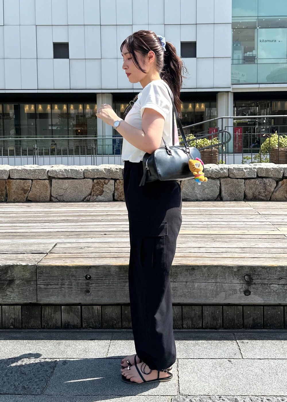 ブラック系のカーゴパンツ、ブラック系のサンダル、ホワイト系のTシャツ/カットソーを着用したレディースの夏コーディネートの5枚目の写真