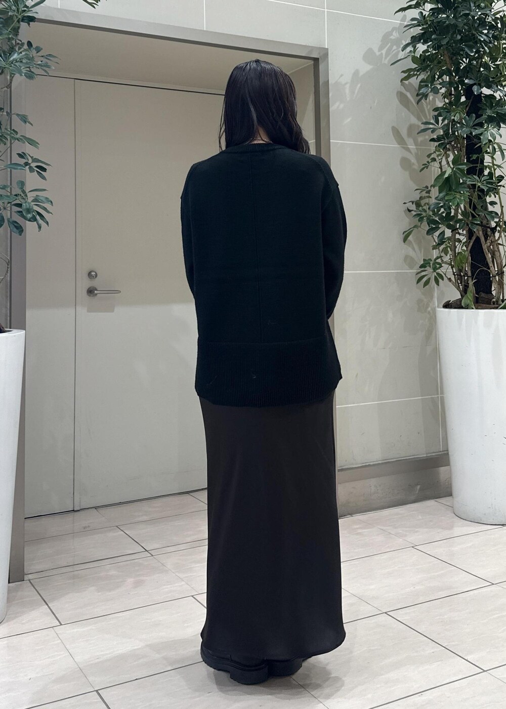 ブラック系のニット/セーター、ブラック系のショルダーバッグ、ブラウン系のスカートを着用したレディースの冬コーディネートの5枚目の写真