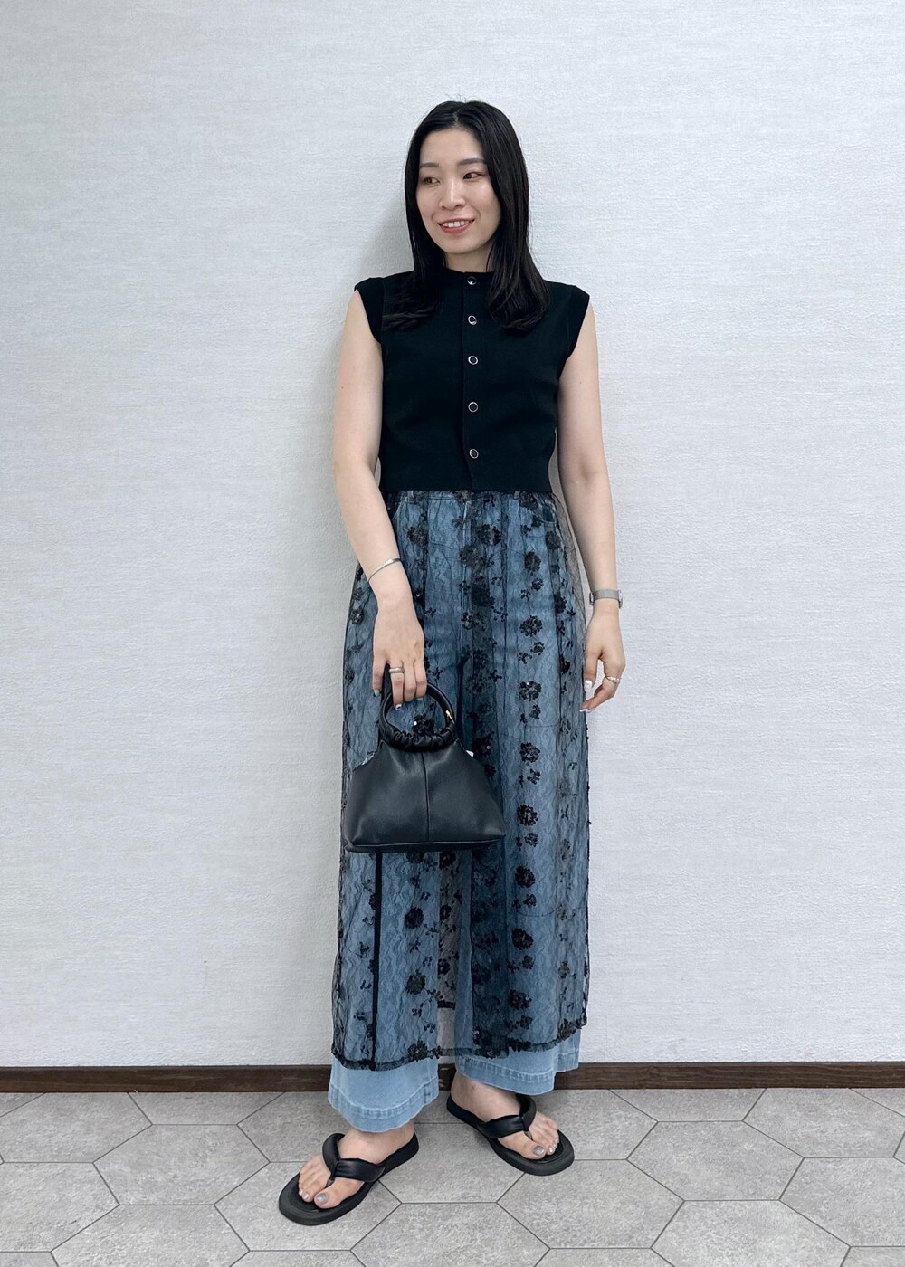 ブルー系のデニムパンツ、ブラック系のベスト、ブラック系のショルダーバッグを着用したレディースの夏コーディネートの4枚目の写真