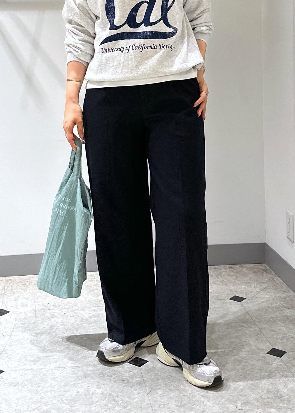 グレー系のスウェット、ブルー系のトートバッグ、ブルー系のスラックスを着用したレディースの夏コーディネートの5枚目の写真