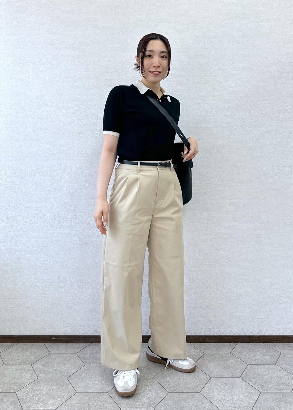 ベージュ系のチノパンツ、ブラック系のトートバッグ、ブラック系のポロシャツを着用したレディースの春コーディネートの3枚目の写真