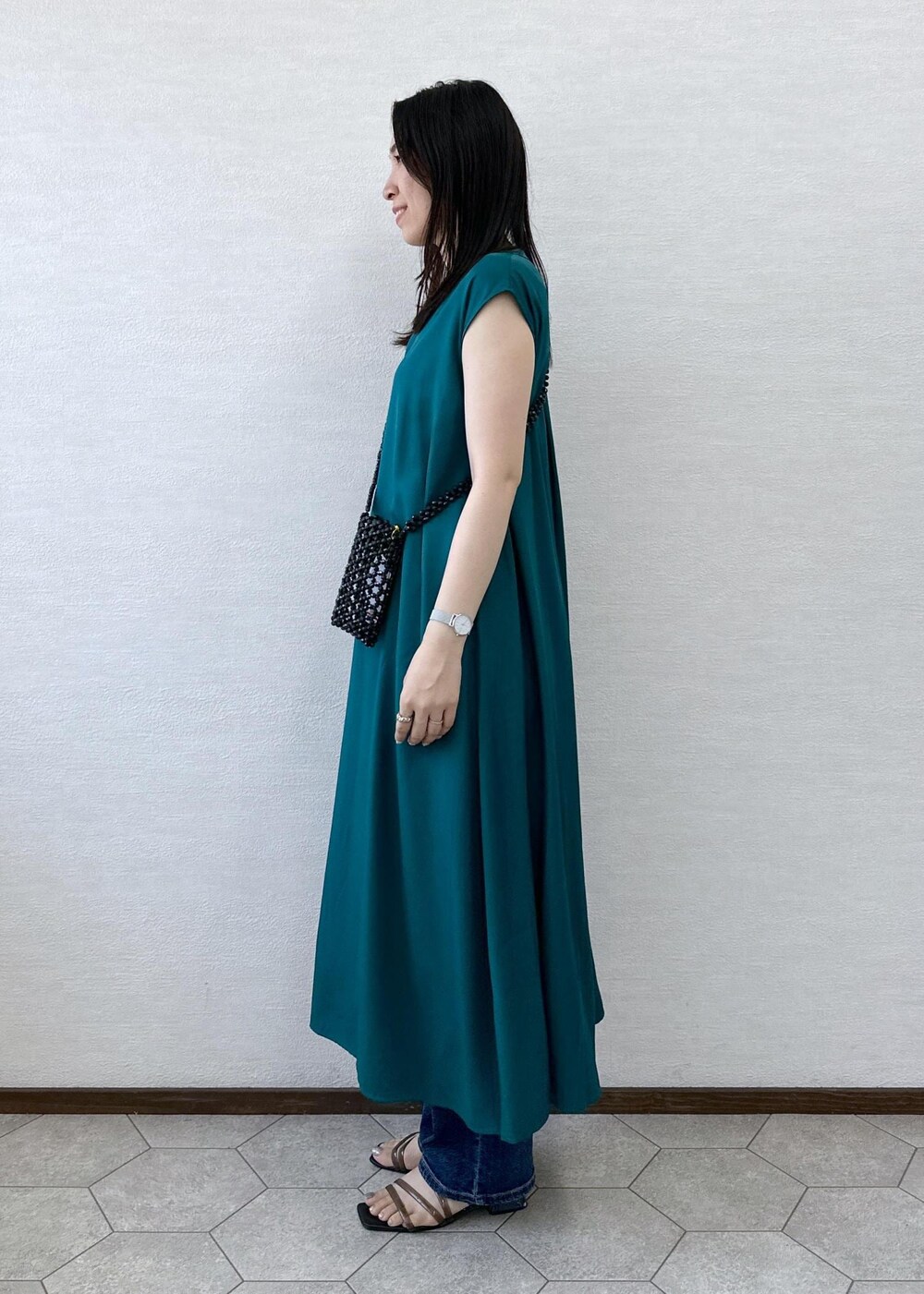 ブラック系のショルダーバッグ、ブルー系のデニムパンツ、グリーン系のワンピースを着用したレディースの夏コーディネートの4枚目の写真