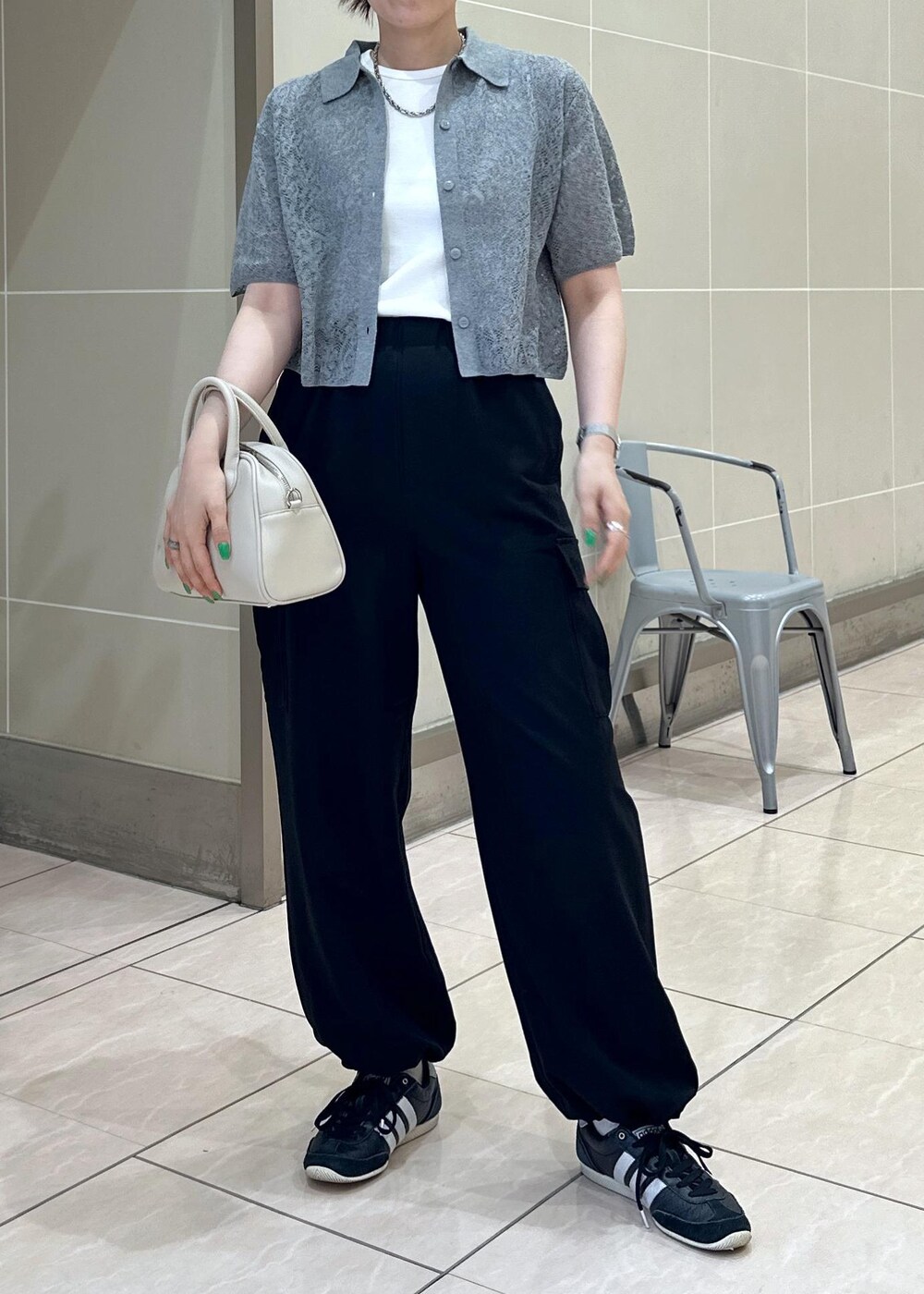 ベージュ系のボストンバッグ、ブラック系のカーゴパンツ、ホワイト系のタンクトップを着用したレディースの夏コーディネートの6枚目の写真