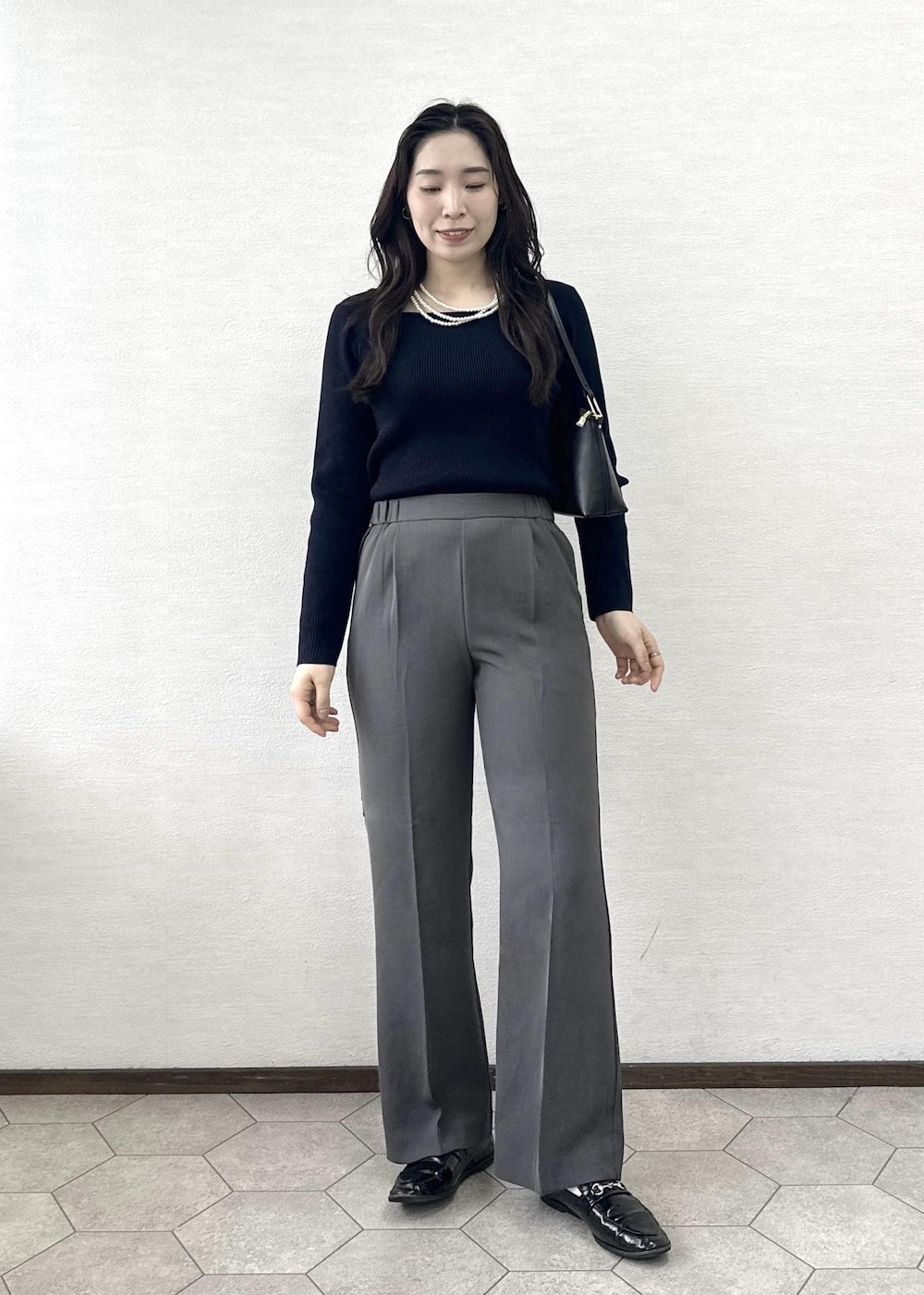 ブラック系のショルダーバッグ、ブルー系のニット/セーター、ベージュ系のトレンチコートを着用したレディースの春コーディネートの8枚目の写真